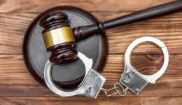 Gavel with stand and handcuffs on the wooden background. Top view.
