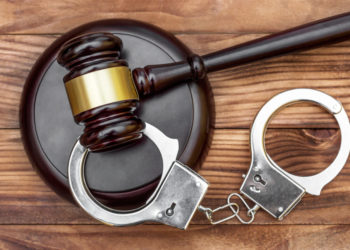 Gavel with stand and handcuffs on the wooden background. Top view. Gavel with stand and handcuffs on the wooden background. Top view.