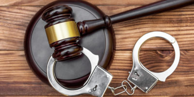 Gavel with stand and handcuffs on the wooden background. Top view.