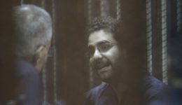 Egyptian activist Alaa Abdel Fattah gestures inside a defendant's cage during his new trial in Cairo, Egypt on May 23, 2015 with 24 other defendants including former Egyptian President Mohammad Morsi on trial for insulting the judiciary. Cairo Criminal court postponed on Saturday, the trial of former President, Morsi, to July 27. [Mostafa el-Shemy/Anadolu Agency/Getty Images